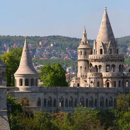 Tours en pierre blanche du Bastion des pêcheurs à Budapest avec flèches coniques et galeries voûtées, surplombant la ville et collines.