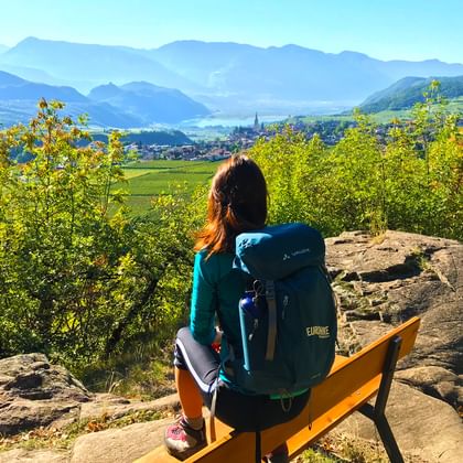 Randonneuse faisant une pause sur un banc et contemplant une vue splendide sur le Lac de Caldaro