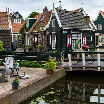Cyclotouriste sur un pont au dessus d'un petit canal de Vollendam en Hollande