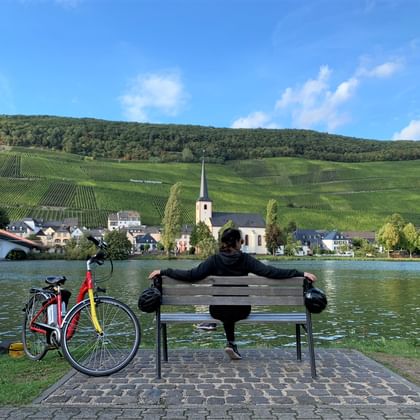 La Moselle à vélo, cyclotouriste se reposant sur un banc sur les rives de la Moselle