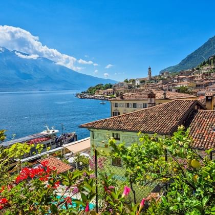 Vue pittoresque de Limone sul Garda avec maisons italiennes traditionnelles, toits de tuiles rouges et jardins luxuriants sur le lac de Garde.