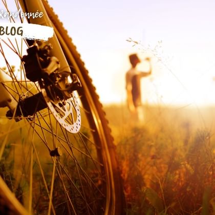 Cycliste buvant en arrière plan de son vélo, dans un champ baigné de soleil