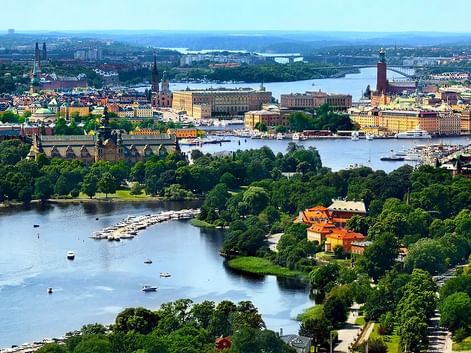Vue panoramique de Stockholm montrant les voies navigables, îles vertes, bâtiments historiques et tour de l'hôtel de ville. Bateaux sur l'eau bleue.