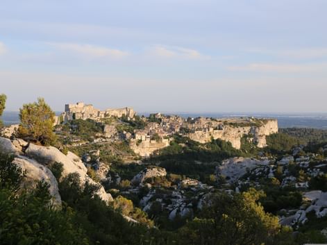 Vue panoramique du village des Baux-de-Provence perché sur des falaises calcaires avec des bâtiments en pierre anciens et des ruines.