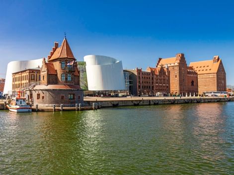 Ozeaneum Stralsund avec architecture moderne blanche courbée à côté de bâtiments historiques en brique au bord de l'eau.