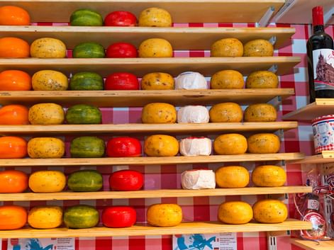 Étalage de meules de Gouda colorées sur étagères en bois à Gouda. Fromages enrobés de cire orange, jaune, verte, rouge et blanche.