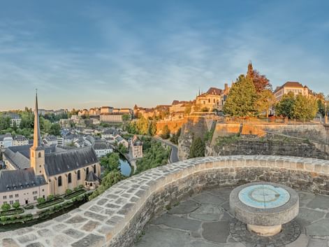 Plateforme circulaire en pierre du Monument du Millénaire avec rose des vents, vue sur la vieille ville de Luxembourg avec clocher et fortifications.