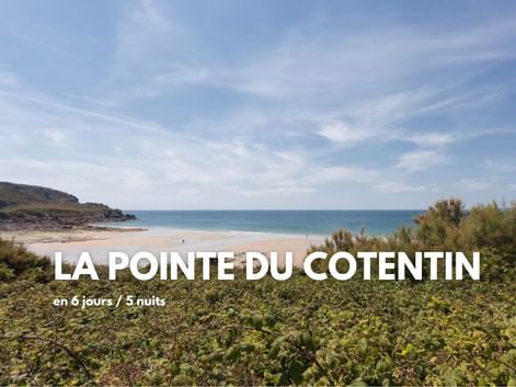 Plage de sable et mer bleue à la Pointe du Cotentin avec végétation côtière au premier plan et promontoire rocheux sous un ciel partiellement nuageux.
