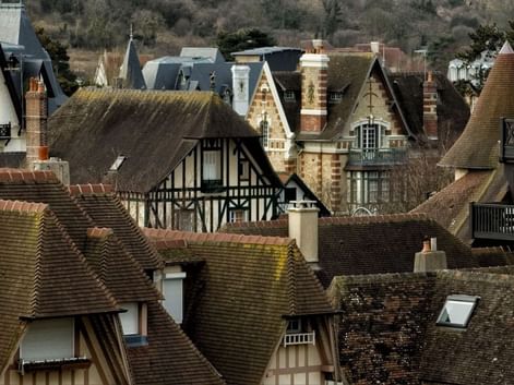 Vue aérienne des toits d'architecture normande traditionnelle à Deauville avec tuiles d'argile, maisons à colombages et cheminées.