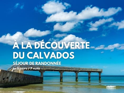 Jetée en béton s'étendant dans l'eau turquoise à Omaha Beach avec un bunker en béton à gauche sous un ciel bleu avec des nuages blancs.