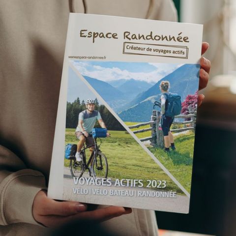 Femme tenant le catalogue d'Espace Randonnée Voyages actifs 2023 
