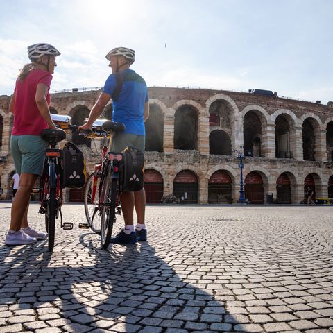 Couple de cyclotouristes devant les arènes de Vérone