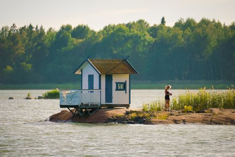 Jeune femme devant une cabane donnant sur une étendue d'eau en Suède