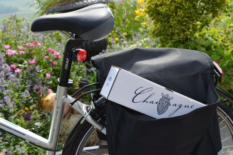 Vélo contenant dans sa sacoche, une bouteille de Champagne emballée