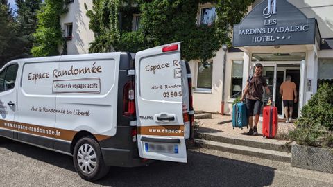 Un membre de l'équipe d'Espace Randonnée transportant les bagages de clients devant un hôtel à Obernai