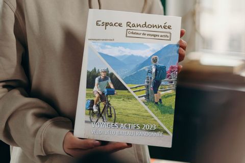 Femme tenant le catalogue d'Espace Randonnée Voyages actifs 2023 