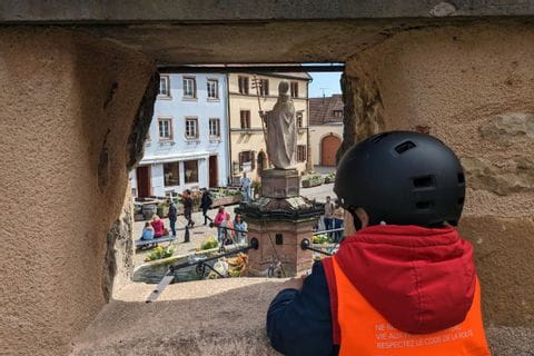 Petit cycliste observant la place principale d'Eguisheim 