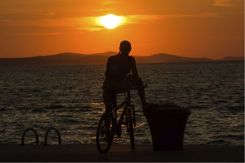 Cycliste admirant la mer près de Porec en Croatie, à contre-jour au soleil couchant
