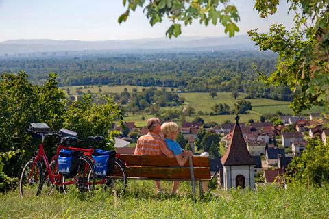 Couple de cyclotouristes profitent d'une pause détente sur un banc surplombant un vignoble de la Forêt-Noire du Sud