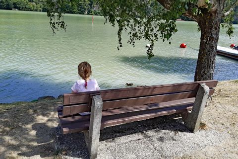 Une jeune enfant assise sur un banc devant le Danube