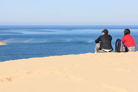 Couple assis sur la Dune du Pilat, contemplant l'océan