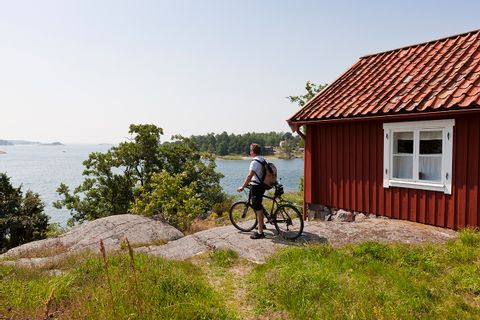 Cycliste devant une maison en bois et un paysage suédois