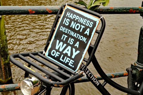 Vélo attaché près d'un quai et portant une pancarte "Happiness is not a destination, it is a way of life."