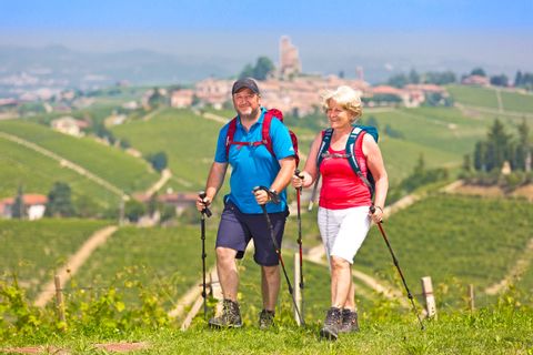 Couple de randonneurs dans le Piémont, avec en arrière plan, le village médiéval de Serralunga d'Alba