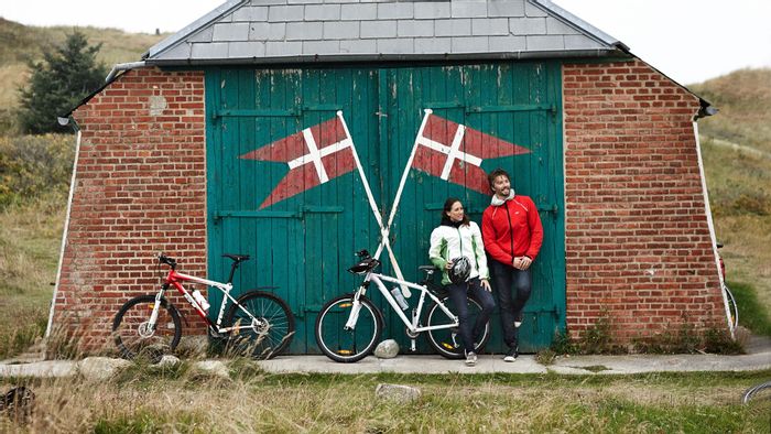 Cyclistes en pause devant une construction peinte de drapeaux danois