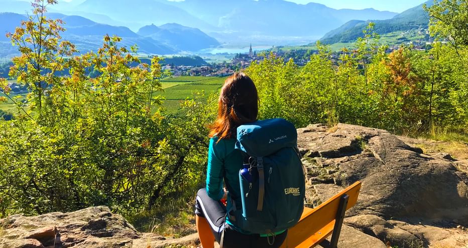 Randonneuse faisant une pause sur un banc et contemplant une vue splendide sur le Lac de Caldaro