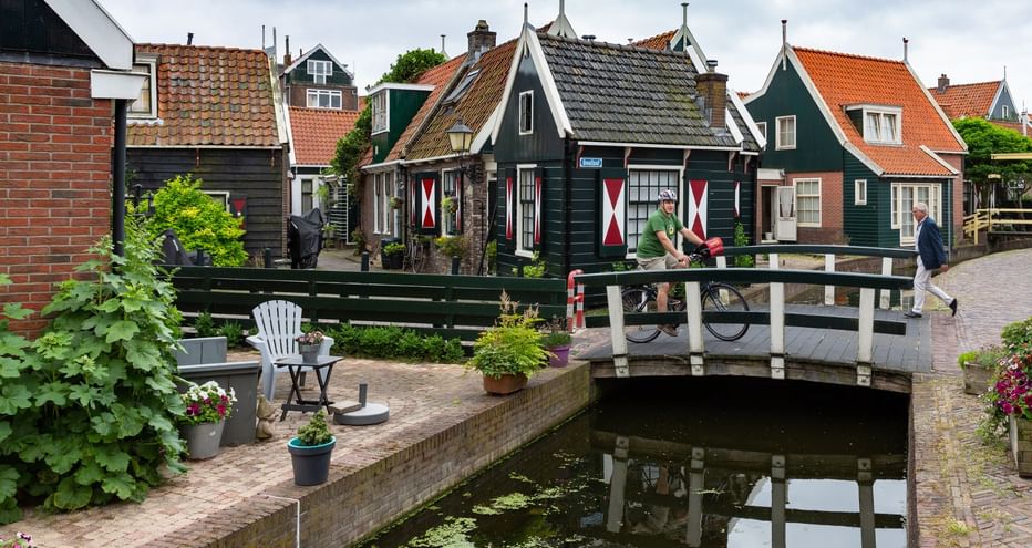 Cyclotouriste sur un pont au dessus d'un petit canal de Vollendam en Hollande