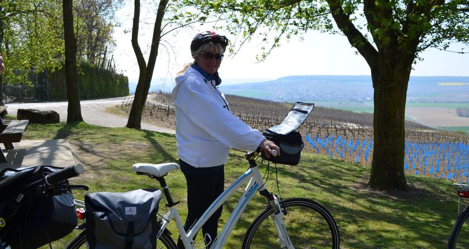 Cyclotouriste posant devant un vignoble de Champagne avec son vélo